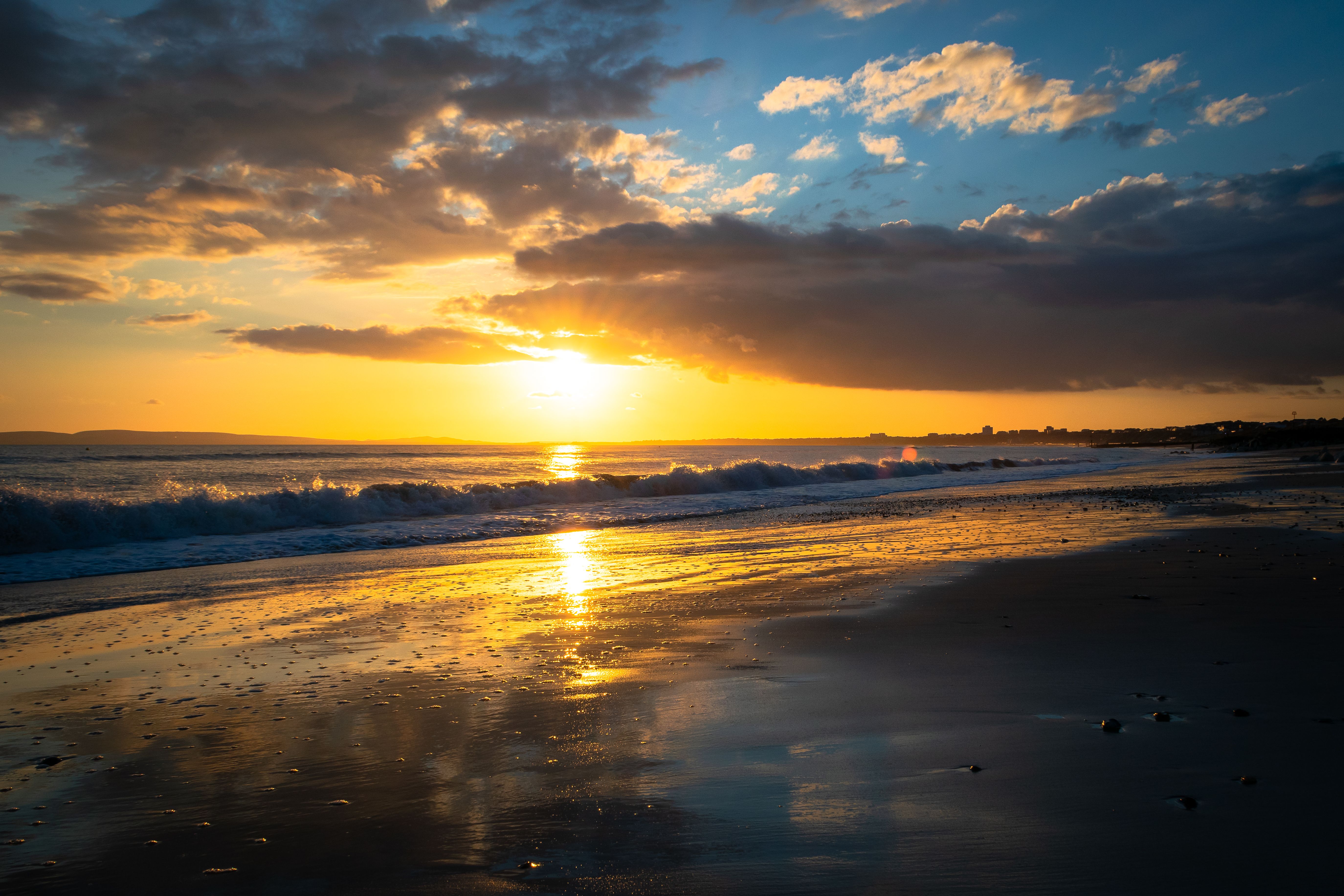 A sunset on the beach with waves and sand · Free Stock Photo