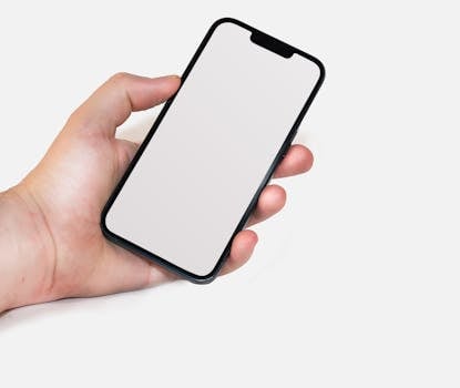 A hand holding a smartphone with a blank screen, perfect for mockups and design templates.