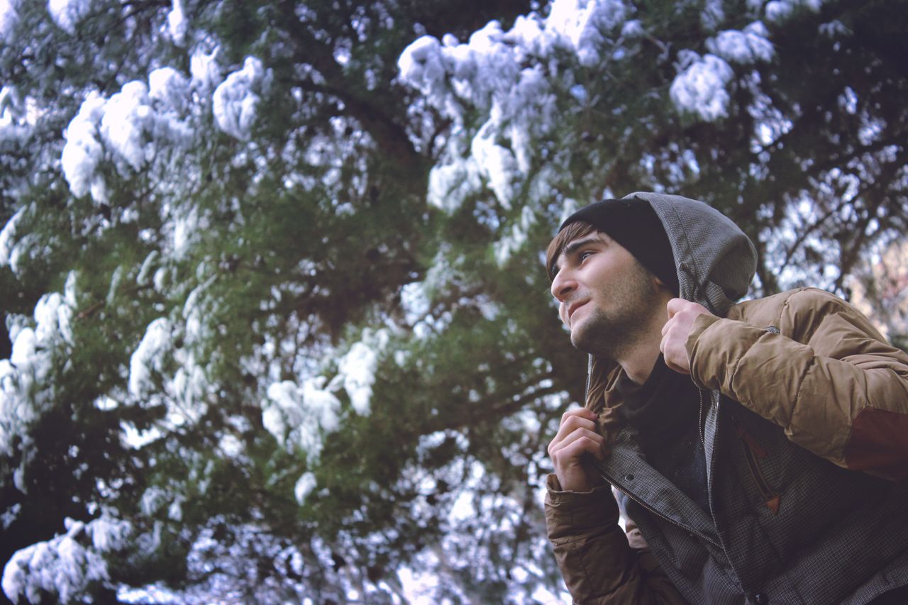 a young man in winter attire enjoys the snowy outdoors in a park in ba