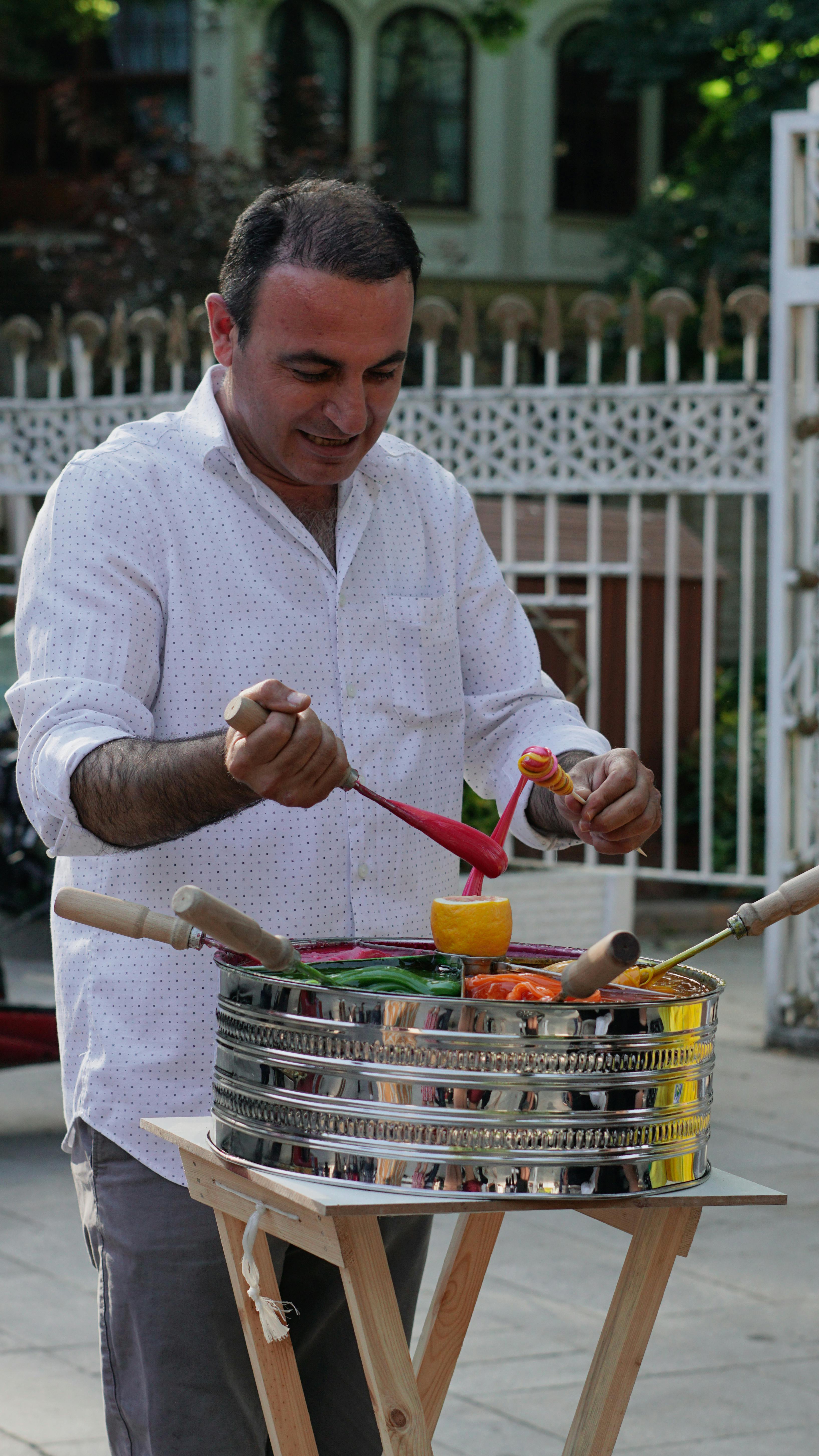 Man preparing traditional Turkish ice cream on the street with vibrant colors.