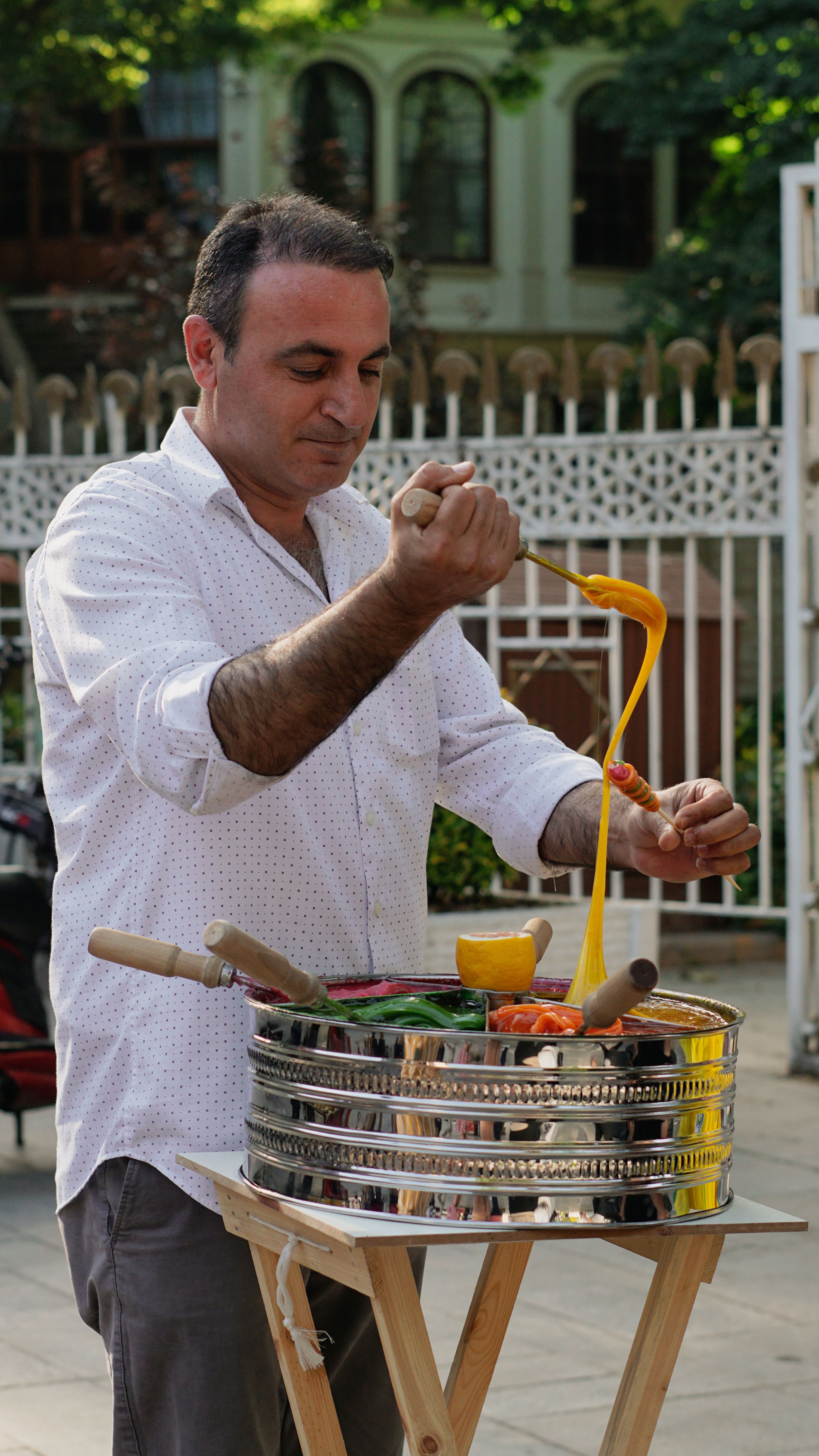Man skillfully preparing stretchy traditional ice cream outdoors. Vibrant street scene.