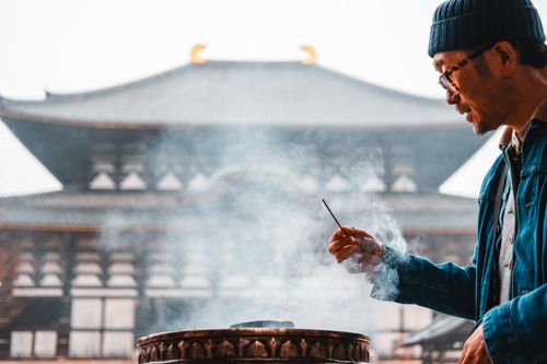 Free A man holds an incense stick at Todaiji Temple in Nara, Japan, enveloped by rising smoke. Stock Photo