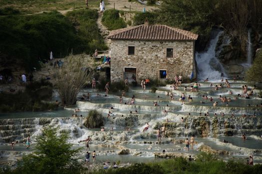 Explore the cascading natural hot springs of Cascate del Mulino in Tuscany, Italy, a serene relaxation spot.