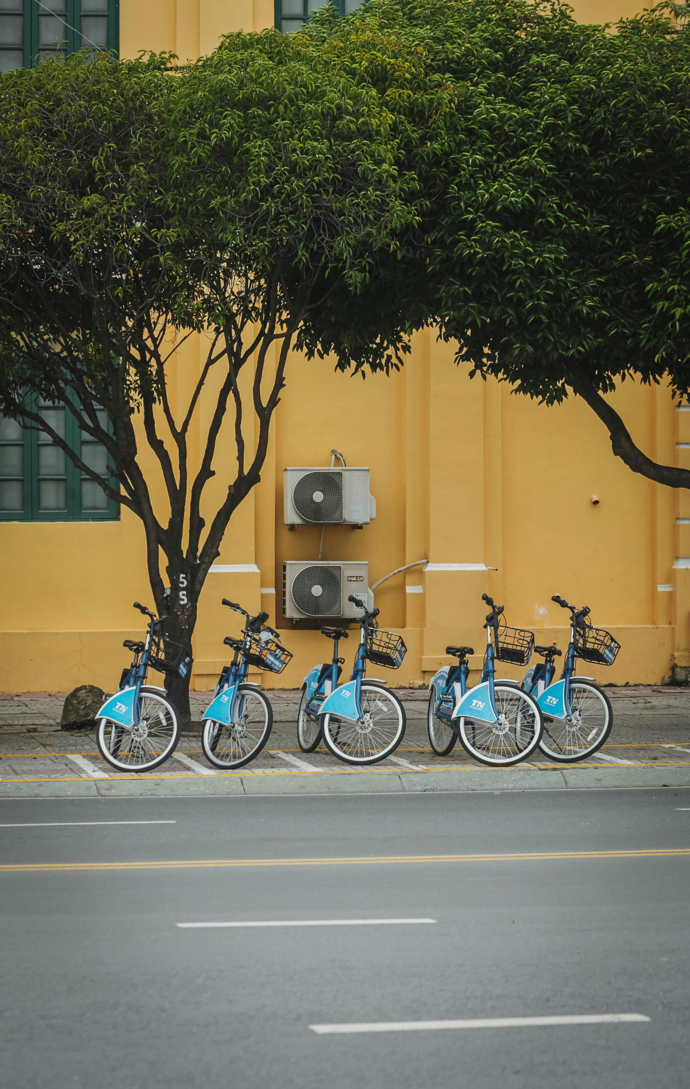 Free Four blue bicycles parked by a yellow building in Ho Chi Minh City, Vietnam. Stock Photo
