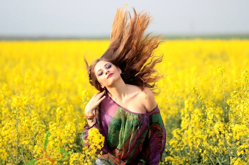 フィールドに黄色い花を持つ若い女性の肖像画