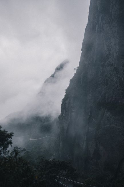 Dramatic mist covers towering cliffs in a scenic landscape, embodying nature's mystery.