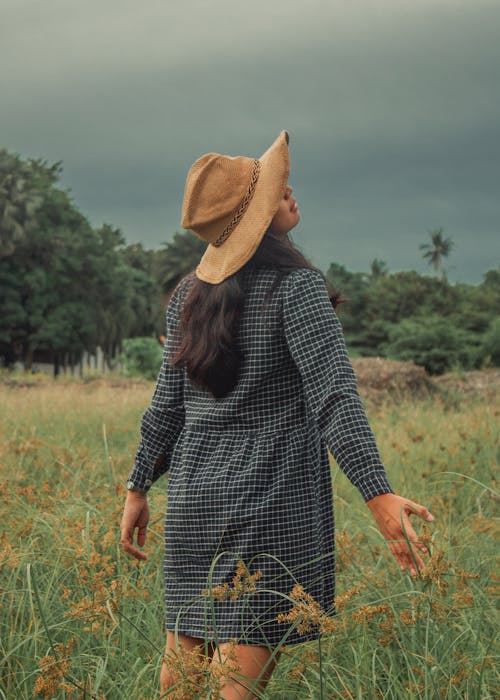 Anonymous woman walking in green field