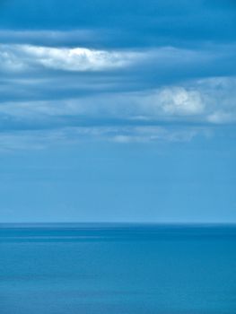Calm ocean scene with a peaceful horizon and overcast clouds, perfect for a tranquil background.