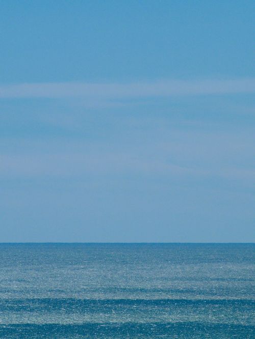 Free Tranquil seascape with a vast blue ocean meets the sky at the horizon under a clear sunny day. Stock Photo