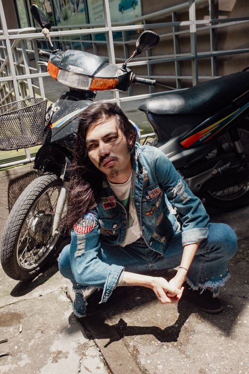 Free Stylish young man poses with a motor scooter outdoors, squatting in sunlight. Stock Photo