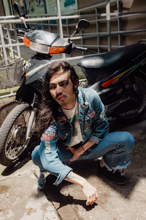 Man with Long Hair and in Jean Jacket Squatting