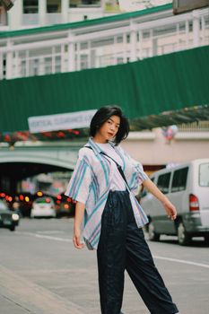 Young woman posing stylishly on a bustling city street during the day.
