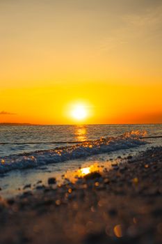 Capture the serene beauty of a sunset at the beach with golden skies over the ocean waves.