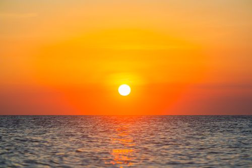 Free Vibrant sunset over a tranquil ocean horizon, creating a serene and moody atmosphere. Stock Photo