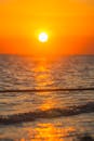 A person is surfing on the beach at sunset