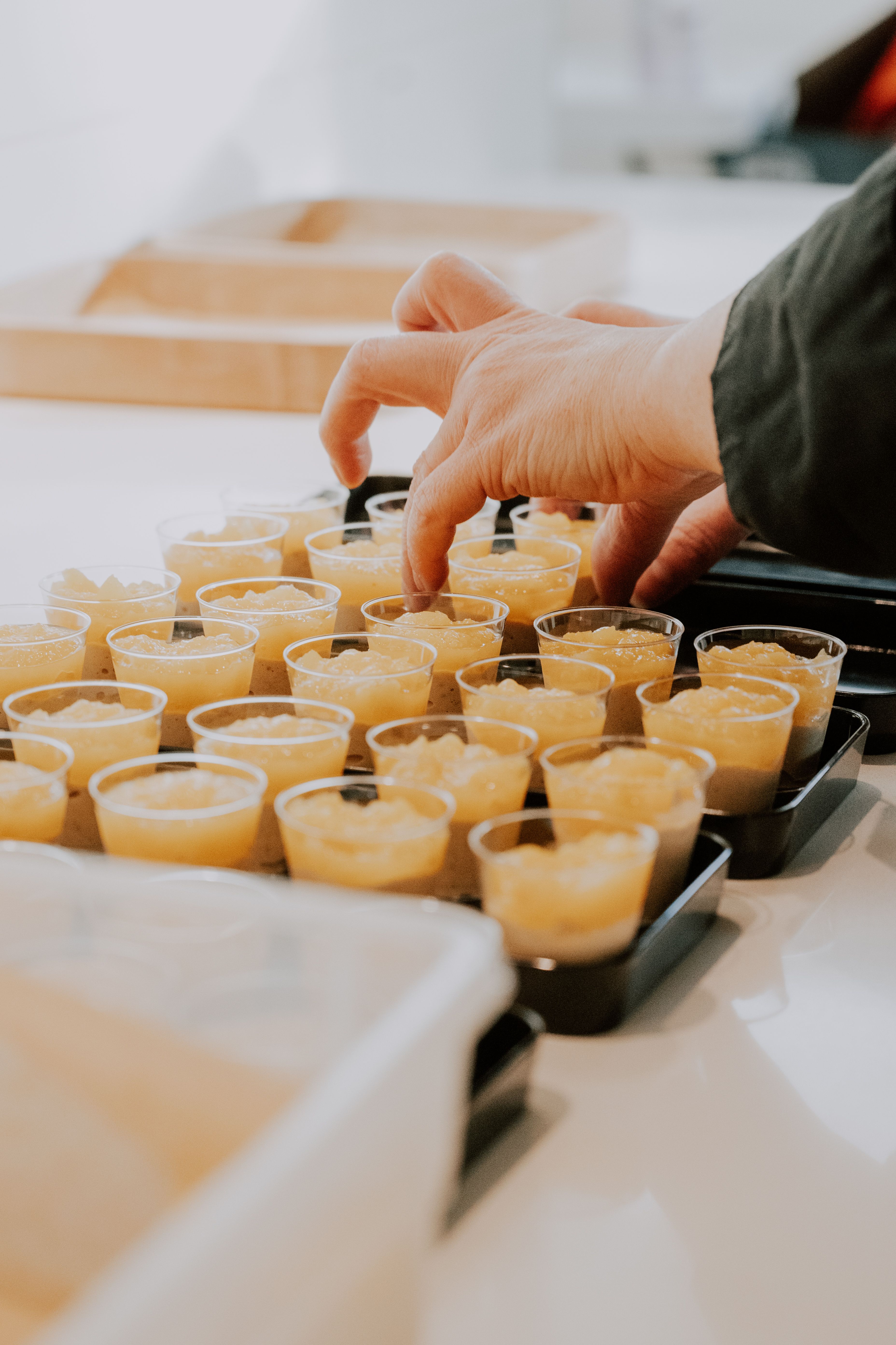 Hand arranging small dessert shots on a tray, perfect for catering and events.