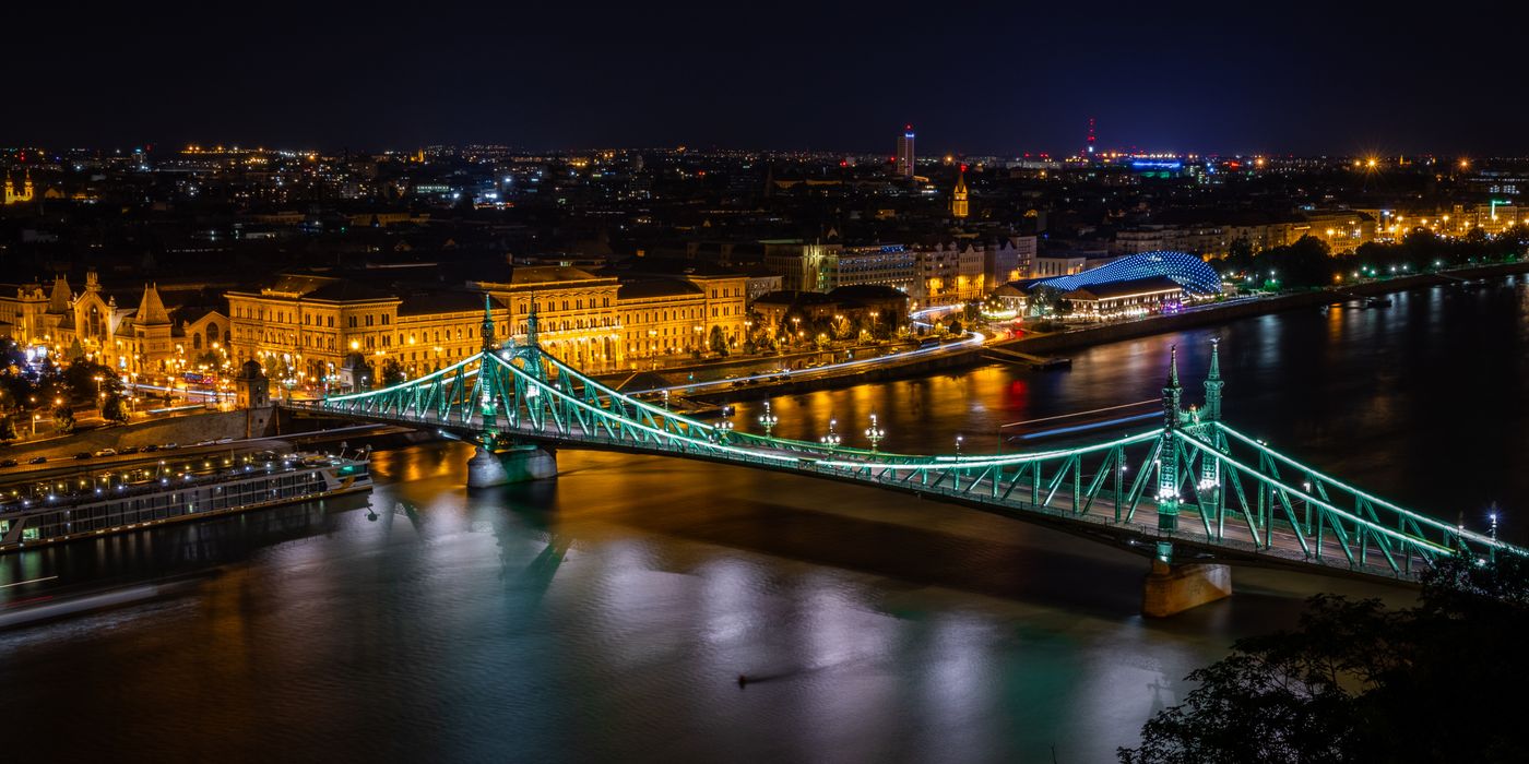 Freedom Bridge in Budapest beautifully lit across the Danube River at night, showcasing the city skyline.