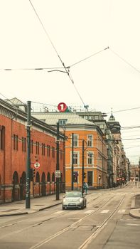 A car drives through an Oslo street lined with vintage architectural buildings under soft daylight.