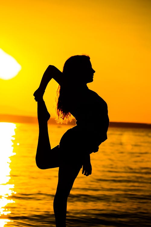 Free Woman Standing on Beach during Sunset Stock Photo
