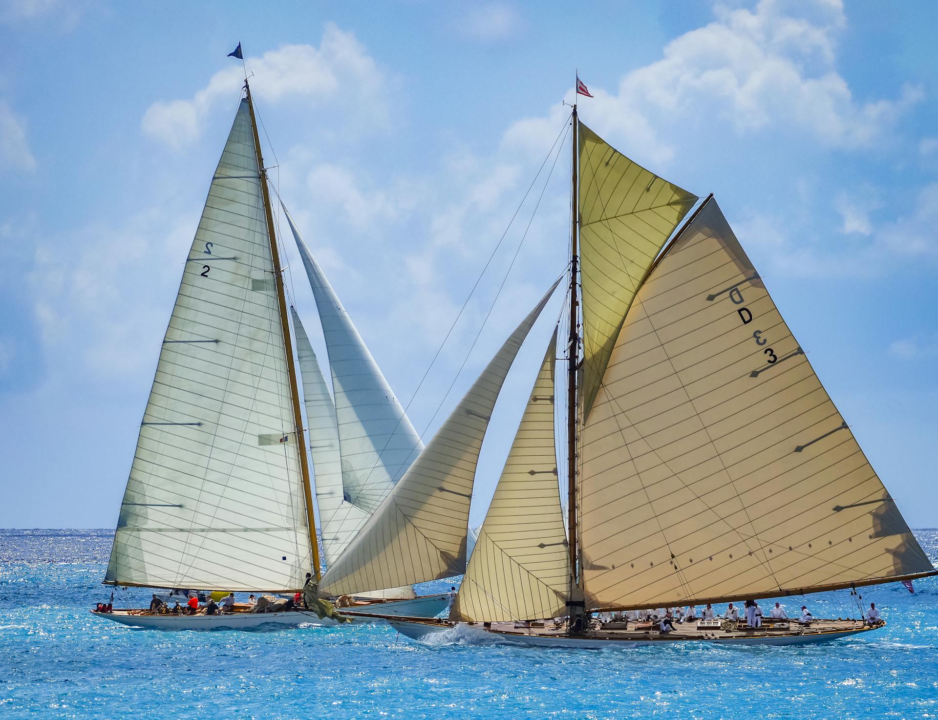 Classic racing yachts compete under cloudy skies in Antibes, France, showcasing sailing elegance.