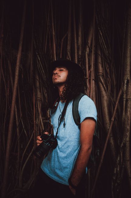 Young photographer in nature holding a DSLR camera, embodying modern lifestyle and exploration.