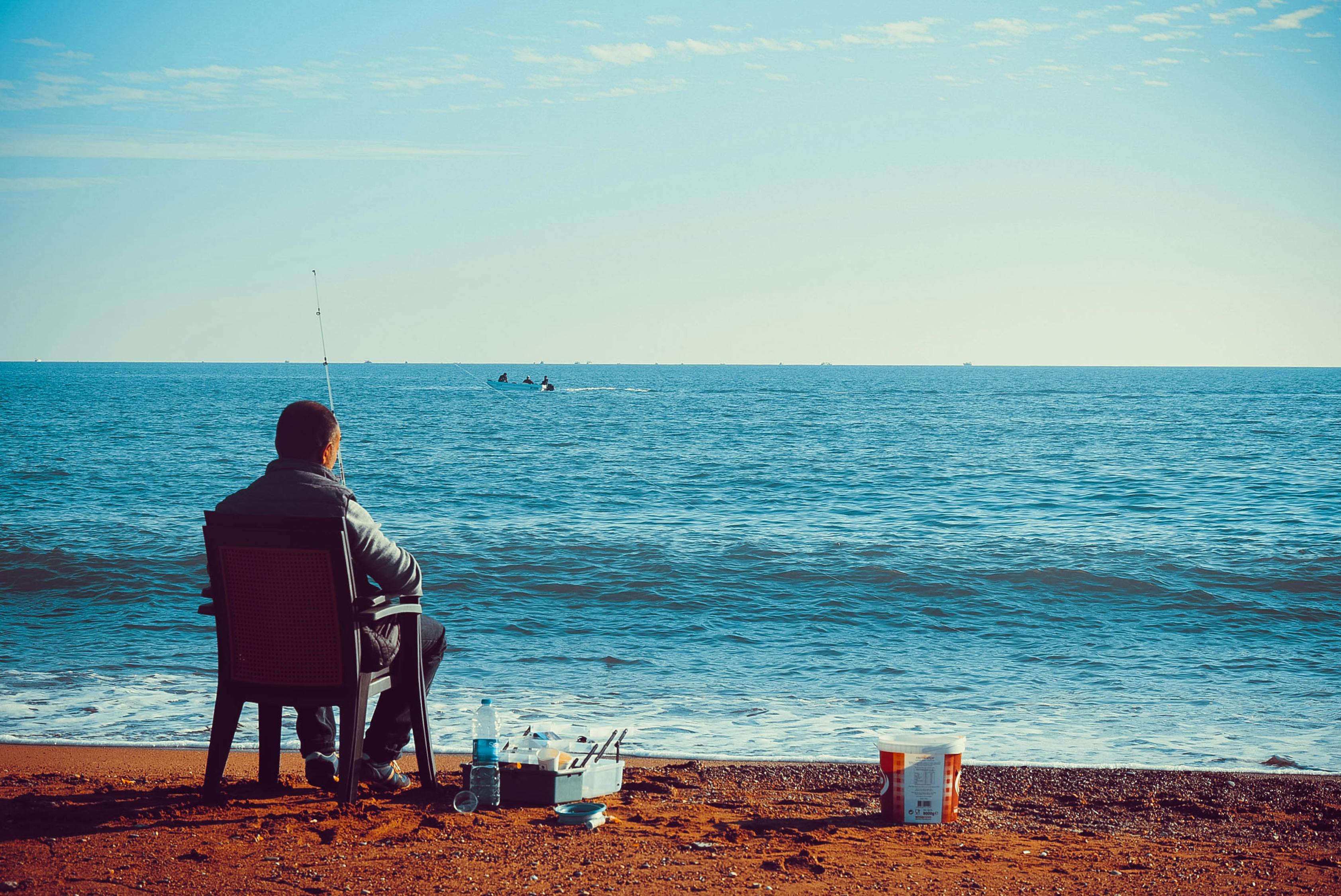 Man sitting on a chair while fishing at the sea shore