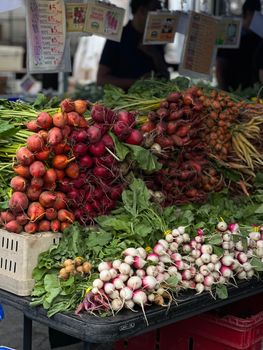 Photo by Natalia S A colorful display of fresh radishes at an outdoor farmer's market stall.