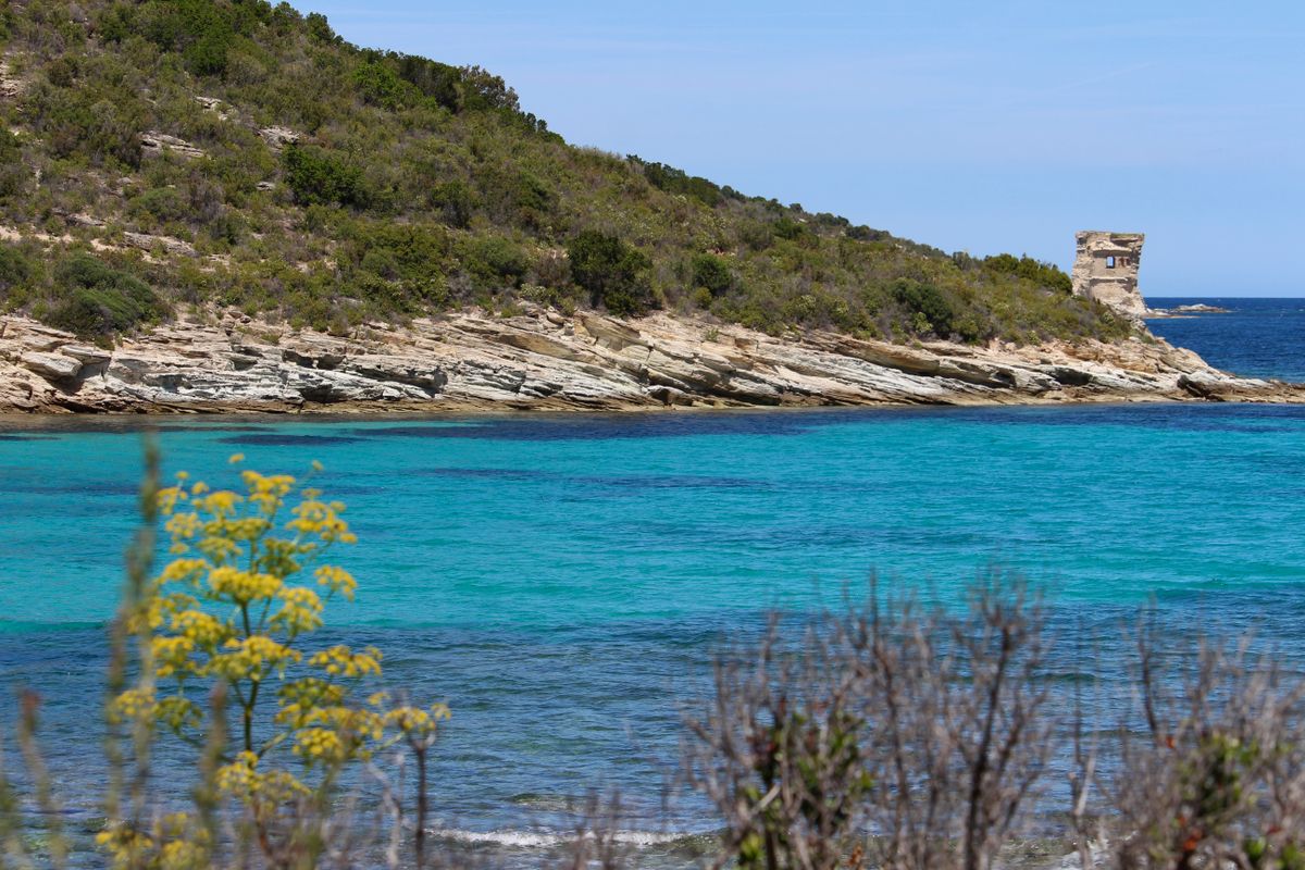 A Genoese watchtower on a headland above brilliant turquoise water