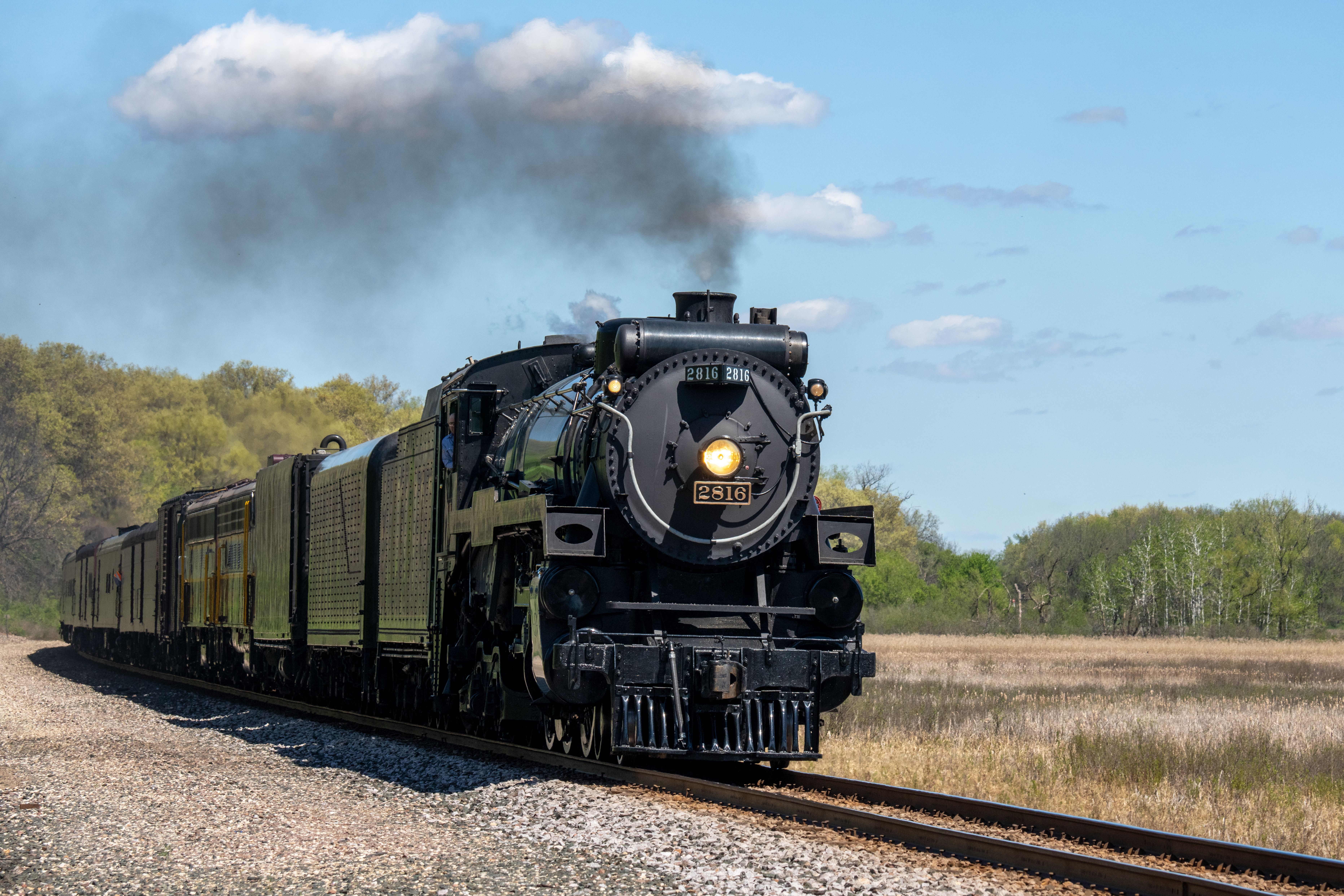 A black train traveling down the tracks with smoke coming out of the ...