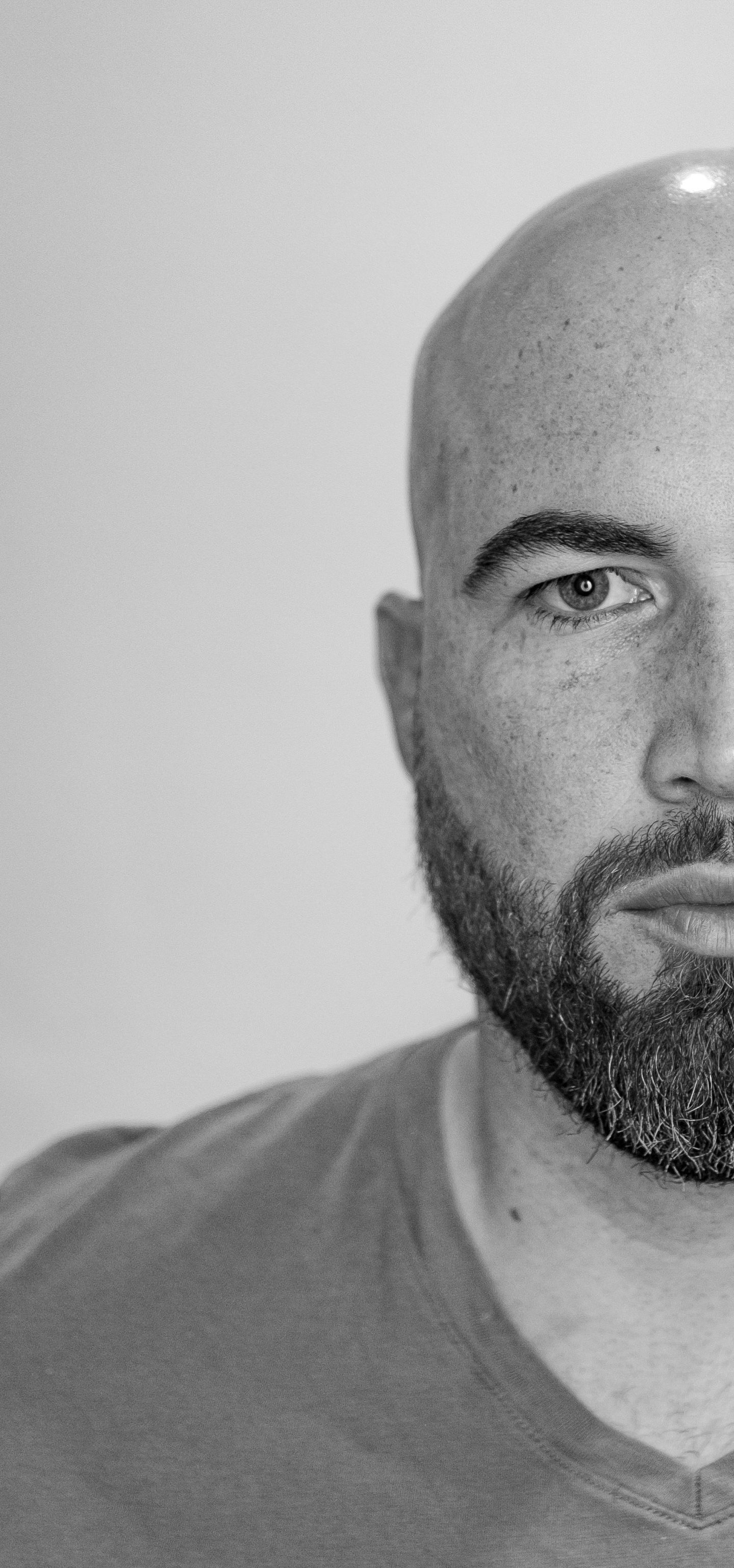 Black and white portrait of a bald man with beard and mustache, serious expression.