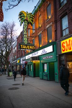 Evening street view of El Mocambo Tavern in a lively city setting with neon lights.