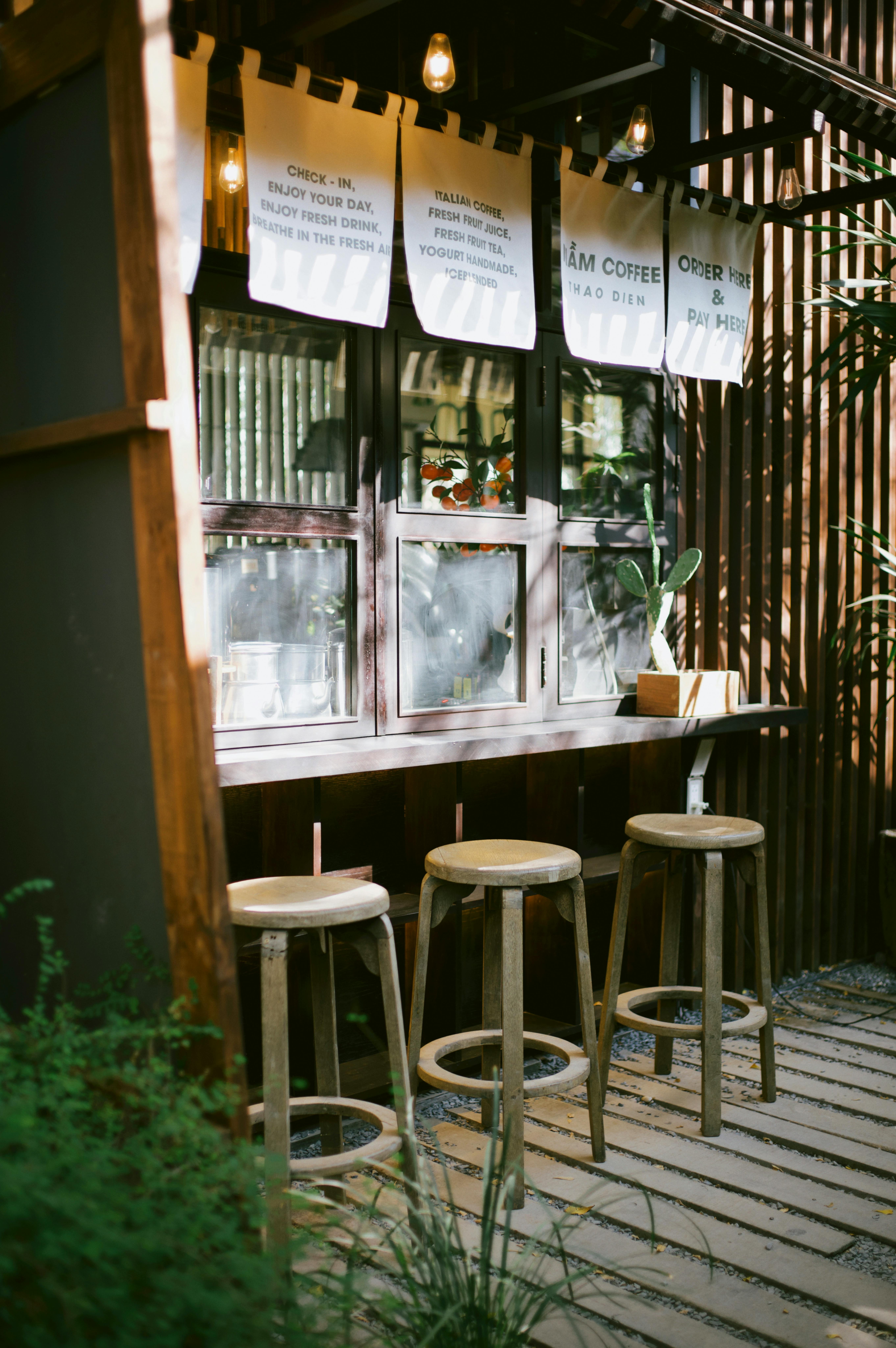 Charming outdoor café setting featuring wooden stools and hanging décor, perfect for a relaxing day.