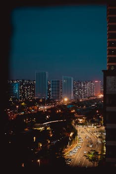 A bustling city skyline at night showcasing illuminated roads and high-rise buildings.