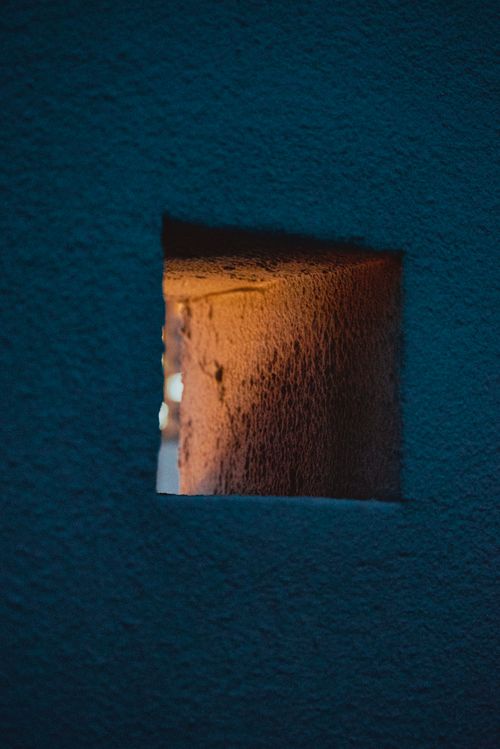Free Artistic shot of a wall hole revealing warm sunset light, creating contrast with the blue wall. Stock Photo