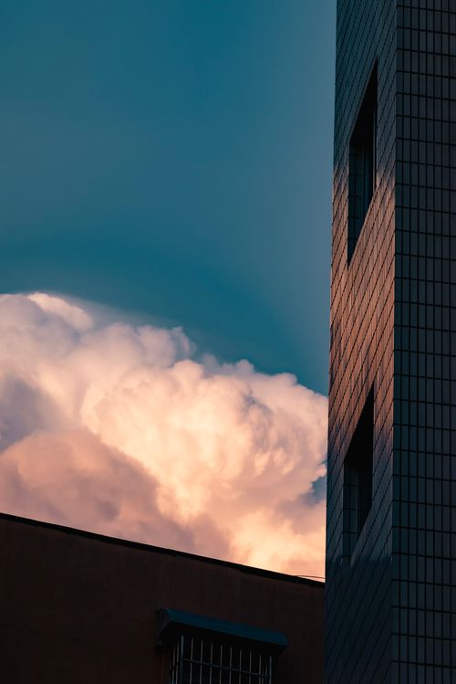 Free Vertical shot of a city building against a dramatic cloudy sky at sunset. Stock Photo
