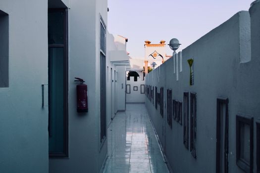 A narrow alleyway with white walls and modern architecture, evoking an urban feel.