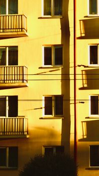 Urban apartment façade lit by warm sunset light, casting long shadows.