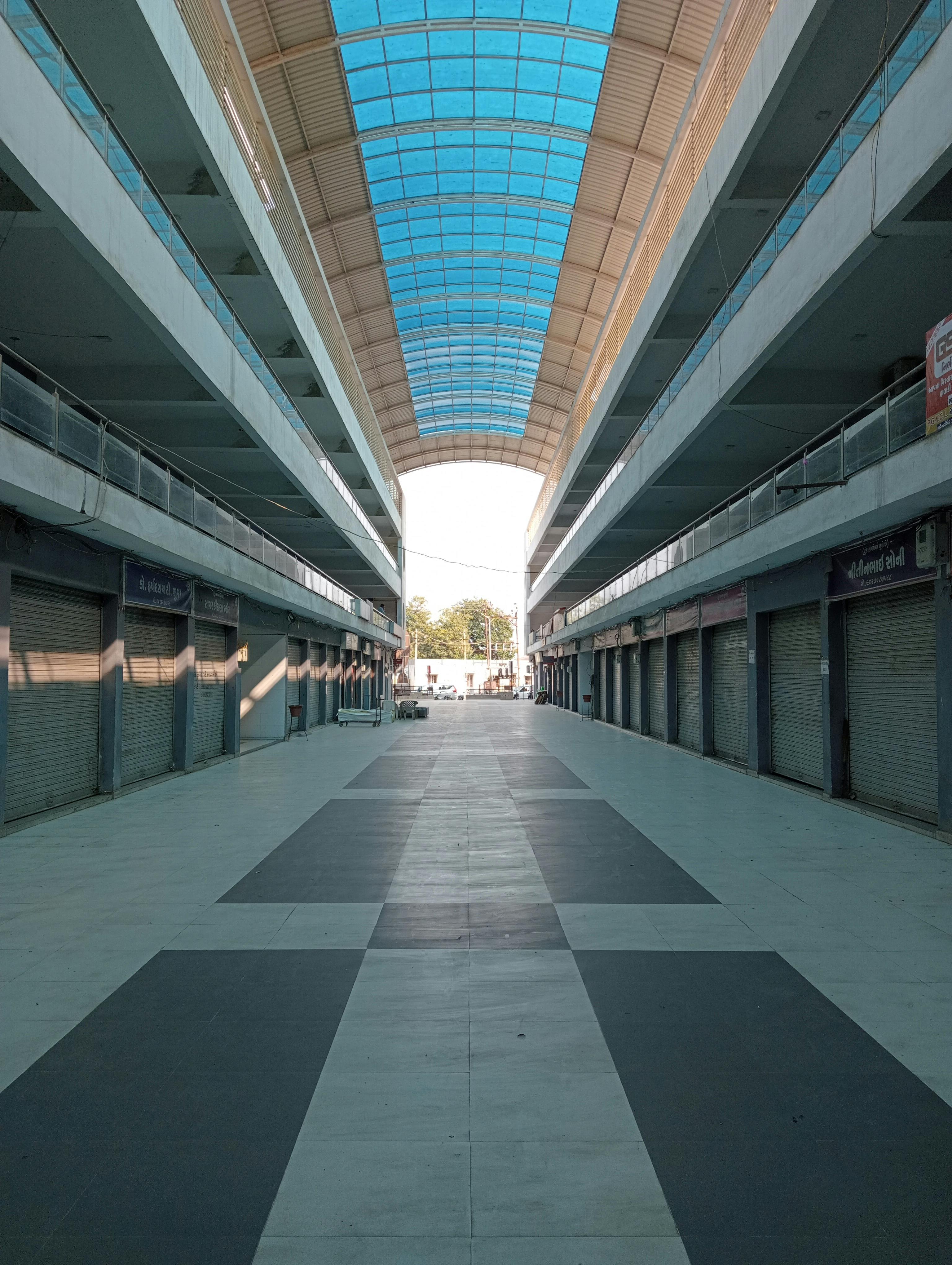 Empty urban market hallway with closed shops and a skylight roof.