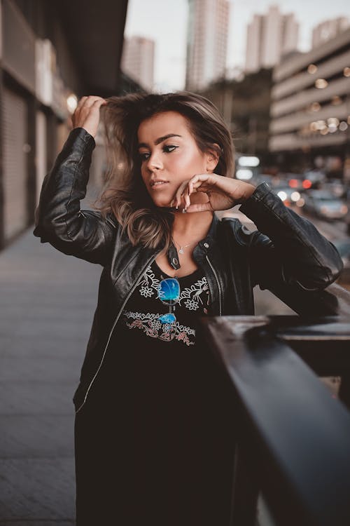 Free Photo of Woman in Black Outfit Standing on Side Walk by Metal Railing Posing While Looking Away Stock Photo
