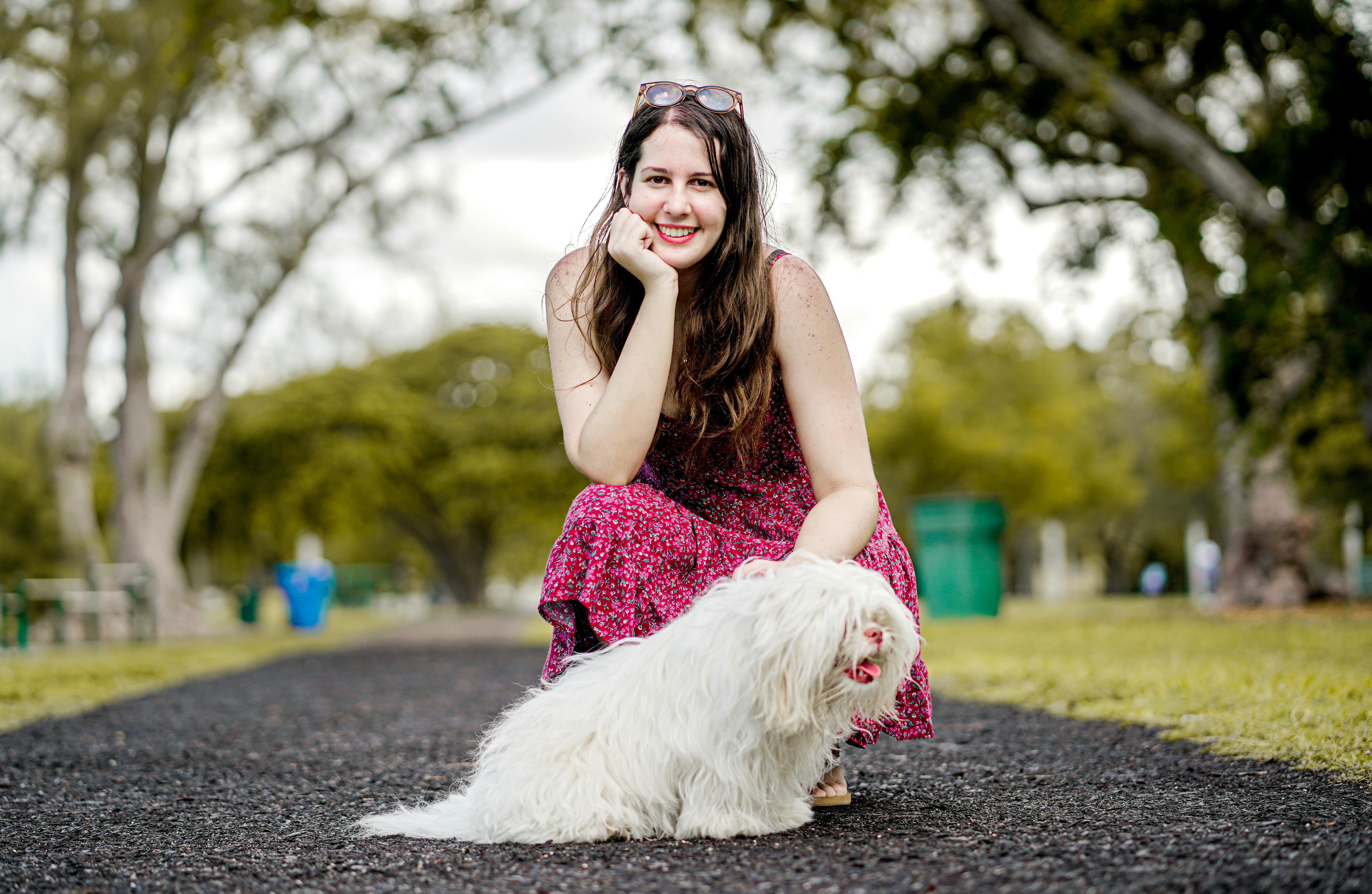 迈阿密公园阳光明媚，一位身穿花卉连衣裙的女子微笑着遛狗