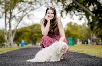 迈阿密公园阳光明媚，一位身穿花卉连衣裙的女子微笑着遛狗