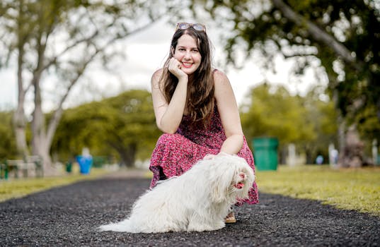 迈阿密公园阳光明媚，一位身穿花卉连衣裙的女子微笑着遛狗