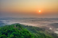 从空中俯瞰，日出景象令人惊叹，郁郁葱葱的绿色景观在雾气笼罩下显得格外宁静