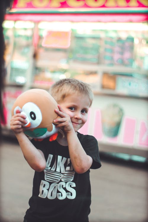 微笑的男孩抱著棕色毛絨玩具的選擇性焦點照片