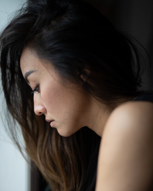Close-up side view of a woman with long hair looking down, conveying elegance and introspection.