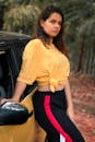 一位年轻时尚的女子在户外黄色汽车旁摆姿势，尽显休闲时尚风范