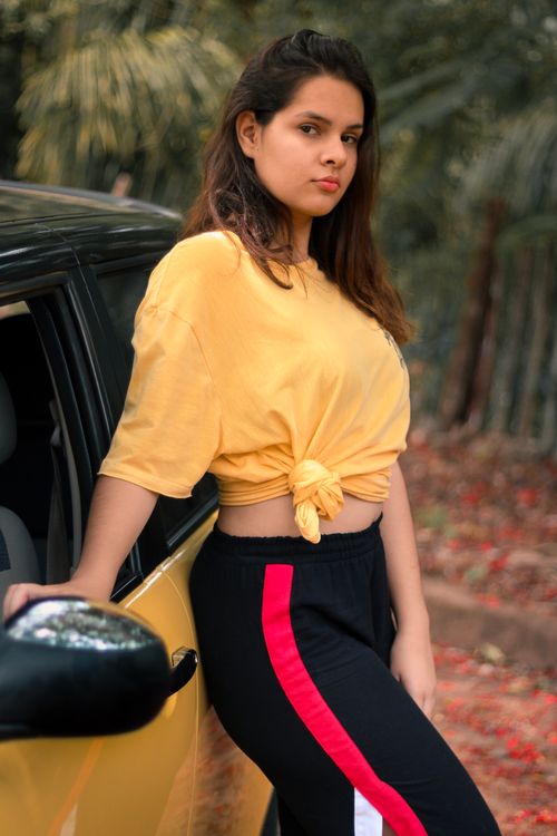 Free Stylish young woman posing outdoors by a yellow car, embracing casual fashion vibes. Stock Photo