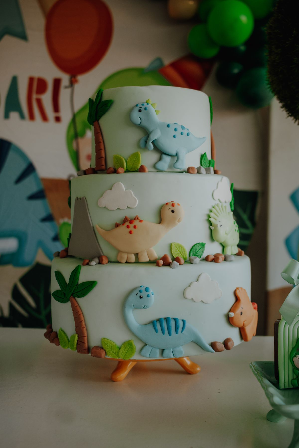 Three-tier dinosaur-themed cake for a children's birthday party. Stock Photo.