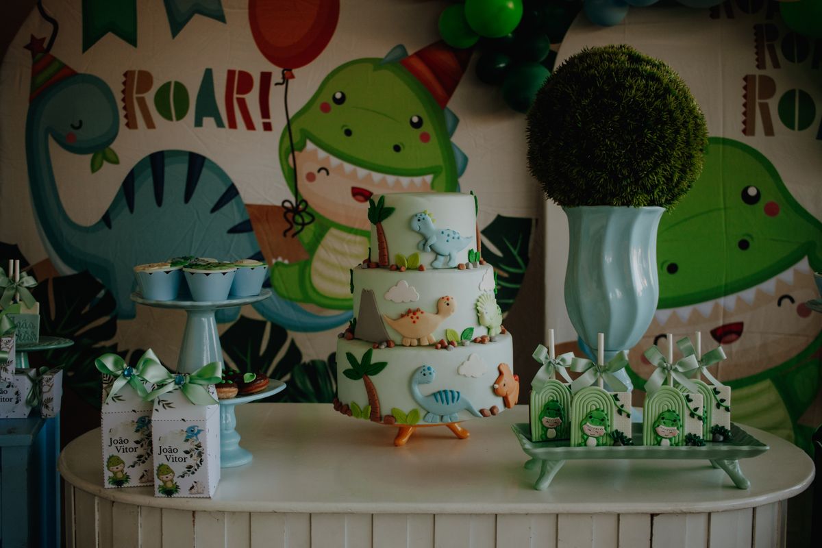 Colorful dinosaur-themed birthday cake and table setup with decorations for a children's party. Stock Photo.