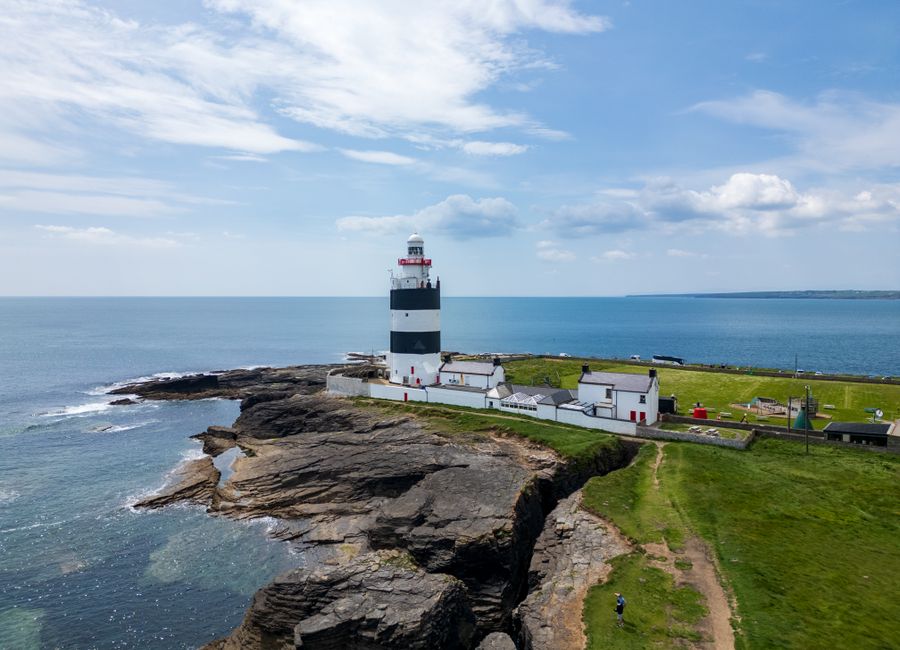 A scenic aerial view of Hook Lighthouse on the rocky coast of County Wexford, Ireland.